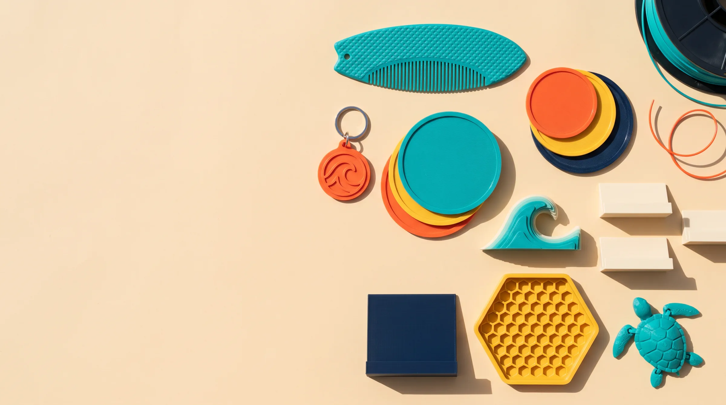 Brand-coloured 3D-printed keyring, coasters, comb, stand and tray on sand
